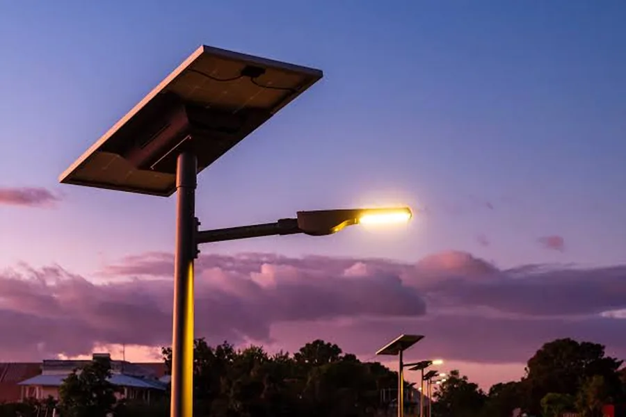 Solar street light with integrated panel illuminated at dusk